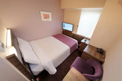 a small bedroom with a bed and a television at Keio Presso Inn Ikebukuro in Tokyo