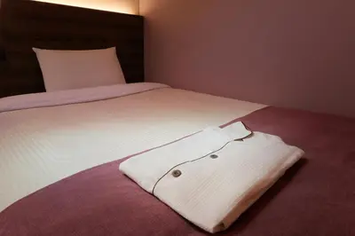 a white shirt is laying on a bed at Keio Presso Inn Ikebukuro in Tokyo