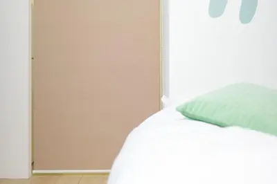 a bed with a green pillow next to a door at Tierra Mukojima in Tokyo