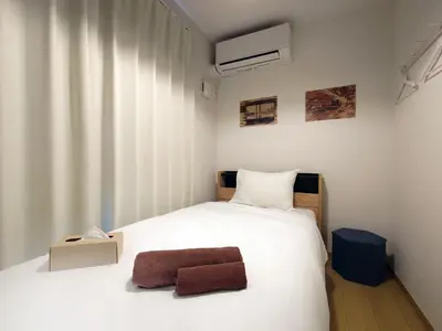 a small bedroom with a white bed with a brown stool at \u51dc\u68ee Rinmori - \u6700\u59277\u540d\u5bbf\u6cca\u53ef - \u6771\u4eac\u30b9\u30ab\u30a4\u30c4\u30ea\u30fc\u307e\u3067\u5f92\u6b69\u570f\u5185 in Tokyo