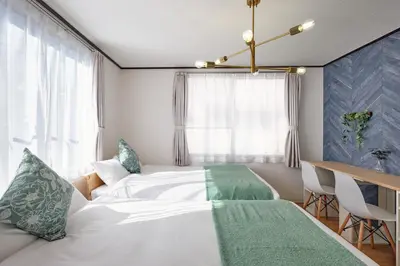 a bedroom with two beds and a desk and a window at Hatagaya Hotel in Tokyo