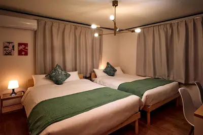 two beds sitting in a room with curtains at Hatagaya Hotel in Tokyo