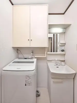a kitchen with a white refrigerator and a sink at Hatagaya Hotel in Tokyo