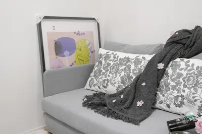 a gray couch with a blanket and pillows on it at Skytree Garden Hotel in Tokyo