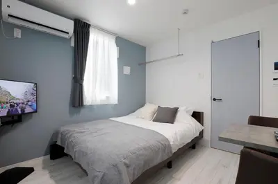 a bedroom with a bed and a tv on a wall at Excellent Arbre in Tokyo