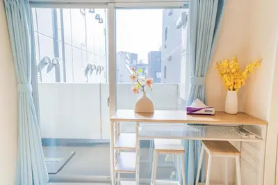 a table with two chairs and a window with blue curtains at 504Room Kinshicho Station 5 min walk near Asakusa and Skytree 5th floor with balcony and good soundproofing in Tokyo