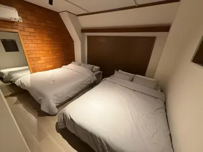 two beds in a room with white sheets and pillows at Villa TOKYO SHIMOTAKAIDO Nest in Tokyo
