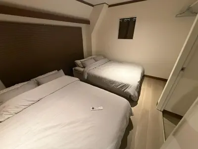 two beds in a small room with white sheets at Villa TOKYO SHIMOTAKAIDO Nest in Tokyo