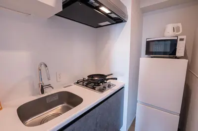 a small kitchen with a sink and a refrigerator at \u6d45\u8349\u99c5\u5f92\u6b69\u570f \u4ea4\u901a\u81f3\u4fbf \u6d45\u8349\u5bfa\u96f7\u9580\u8fd1\u304f \u89b3\u5149 \u30b7\u30e7\u30c3\u30d4\u30f3\u30b0 \u30b0\u30eb\u30e1\u62e0\u70b9 Qs in Tokyo