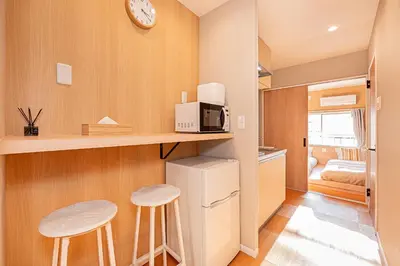 a small kitchen with a microwave and two stools at Komorebi Asakusa Cozy 6P Stay The 77 House Tokyo in Tokyo