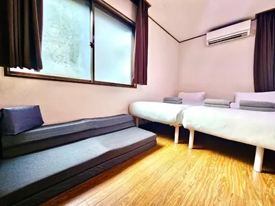 a room with three beds and a window at Credo House Shin-Okubo in Tokyo