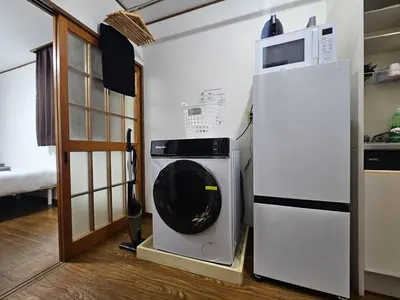 a washing machine in a kitchen next to a refrigerator at Credo House Shin-Okubo in Tokyo