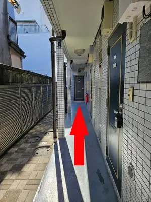 an alley with a red arrow pointing to a door at Credo House Shin-Okubo in Tokyo