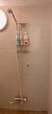 a shower in a bathroom with a white tiled wall at Aila Room in Tokyo