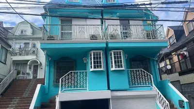 a blue house with a balcony and stairs at Aila Room in Tokyo