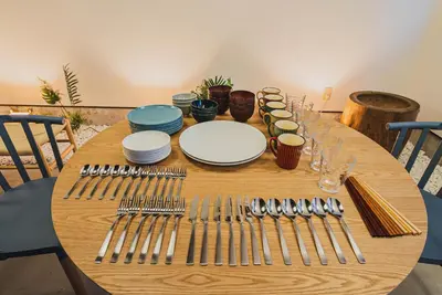 a wooden table with plates and forks and knives at En House Asakusa in Tokyo