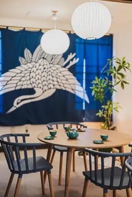 a dining room table with chairs and a blue curtain at En House Asakusa in Tokyo