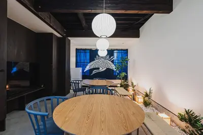 a dining room with a wooden table and blue chairs at En House Asakusa in Tokyo