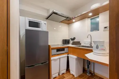 a small kitchen with a refrigerator and a sink at Great location 8 minutes on foot from Higashi-Shinjuku Station and 1 stop from Shinjuku Station! Accommodates up to 11 people Wi-Fi available Shibuya, Asakusa, Ikebukuro in Tokyo