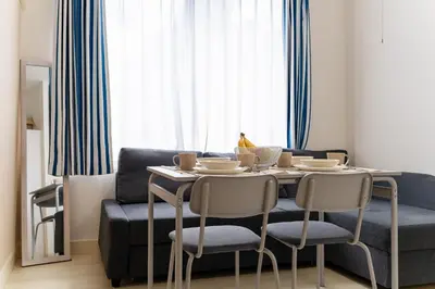 a dining room table with chairs and a blue couch at Private Apartment HOTEL Ceres Kamiikebukuro 401 in Tokyo