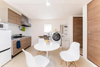 a kitchen with a white table and white chairs at Private Apartment HOTEL Ceres Kamiikebukuro 401 in Tokyo