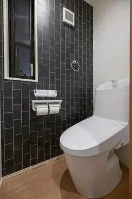 a bathroom with a white toilet and black tiles at Skytree View Riverside Terrace in Tokyo