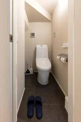 a bathroom with a toilet and a pair of slippers at HoursHouse HD JAPAN in Tokyo