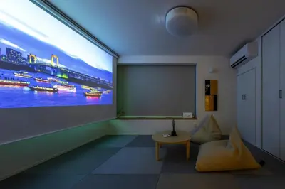 a room with a large projection screen and a table at HoursHouse HD JAPAN in Tokyo