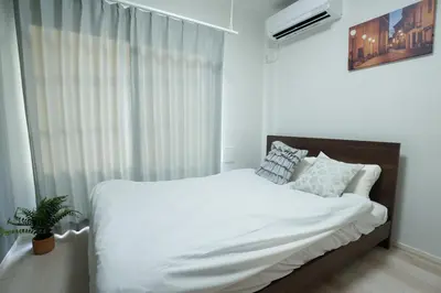a bedroom with a bed with white sheets and a window at \u30b0\u30e9\u30f3\u30b7\u30e3\u30ea\u30aa\u7acb\u82b1 in Tokyo