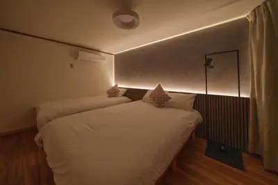 a bedroom with two beds with a light on the wall at INDIGO HOUSE 3-story House, 4BR 8 Beds, Family Friends Welcome - Shinjuku Disney\u6771\u4eac\u30c7\u30a3\u30ba\u30cb\u30fc\u30ea\u30be\u30fc\u30c8 in Tokyo