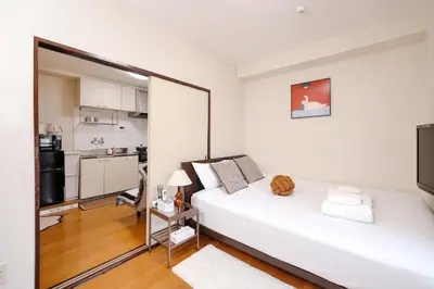a bedroom with a white bed and a kitchen at 3 min JR Near Tokyo Skytree Asakusa Shinjuku Sea Heim in Tokyo