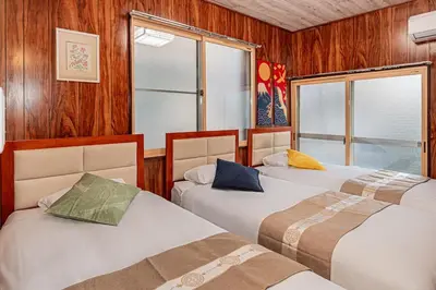 three beds in a room with wood walls and windows at Sky Tree Stay Hotel 5 8-minute walk from Yahiro Station 3-minute train ride to Tokyo Skytree Station in Tokyo