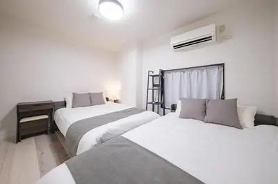 a bedroom with two beds and a desk and a window at MIKASA guesthouse3 in Tokyo