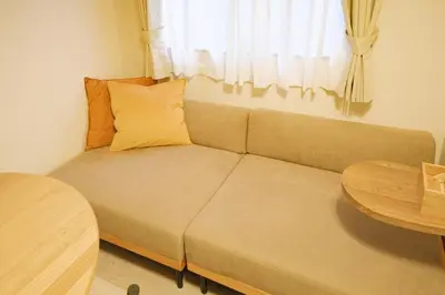a couch in a room with a table and a window at MIKASA guesthouse3 in Tokyo