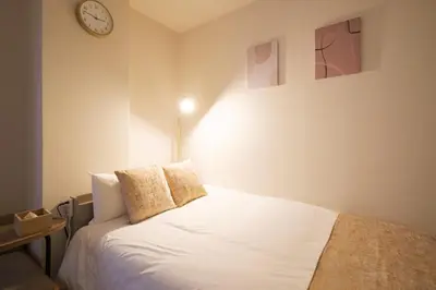 a bedroom with a white bed with a clock on the wall at MIKASA guesthouse3 in Tokyo