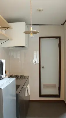 a kitchen with a refrigerator and a door to a room at Hostel Hana An in Tokyo