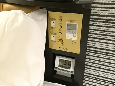 a machine with a clock on it next to a pillow at APA Hotel Roppongi Ekimae in Tokyo