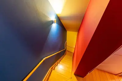 a hallway with colored walls and a stairway with a light at Ikebukuro the Anime Mecca NEO TOKYO BASE Fortuna House in Tokyo