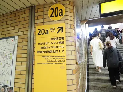 a sign on a building with people walking down the stairs at Ikebukuro the Anime Mecca NEO TOKYO BASE Fortuna House in Tokyo