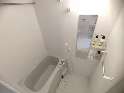 a white bathroom with a tub and a mirror at 101Room,7-minute walk from Uguisudani Station located on the 1nd floor of an apartment-style building Twin room No elevator in Tokyo