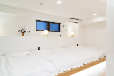 a white bedroom with two beds and a window at ISSHUKU Noma \u5317\u65b0\u5bbf -101 Multiple Beds Room 4-6 Guests in Tokyo