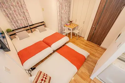 two beds in a small room with a table at Skytree Stay Home, a 4-minute walk from Oshiage Station, a private house with an elevator in Tokyo