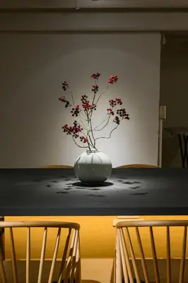 a vase with red flowers in it on a table at Zen Premium Suite Newly Renovated Luxury Home 2King Beds Near Shinjuku in Tokyo