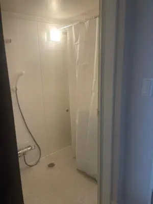a bathroom with a shower with a white shower curtain at Aila apartment in Tokyo