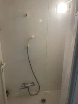 a shower in a bathroom with a light on the wall at Aila apartment in Tokyo