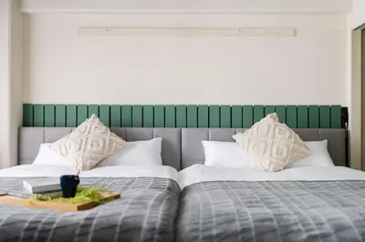two beds with white pillows and a green headboard at Felizstay 907 in Tokyo