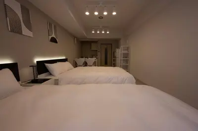 two beds in a room with white sheets at Ruhe Ikebukuro in Tokyo