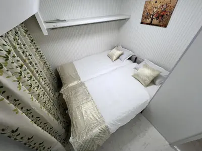 a bedroom with a bed with white sheets and pillows at \u6d45\u8349\u5bfa\u6c11\u6cca in Tokyo