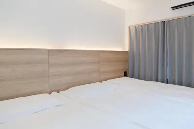 a bedroom with a white bed with a wooden headboard at ISSHUKU Noma \u5317\u65b0\u5bbfI -201 Triple Room in Tokyo