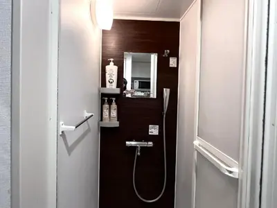 a bathroom with a shower with a sink and a mirror at 新宿Shin-Ōkubo Aeroland 2 in Tokyo
